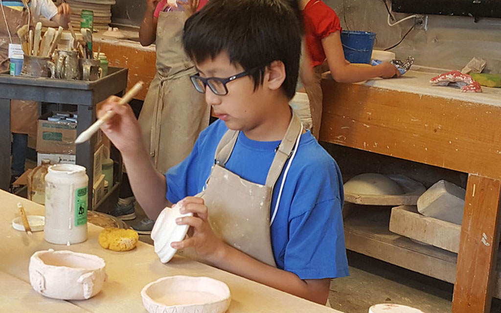 ExplorSchool student painting clay bowls
